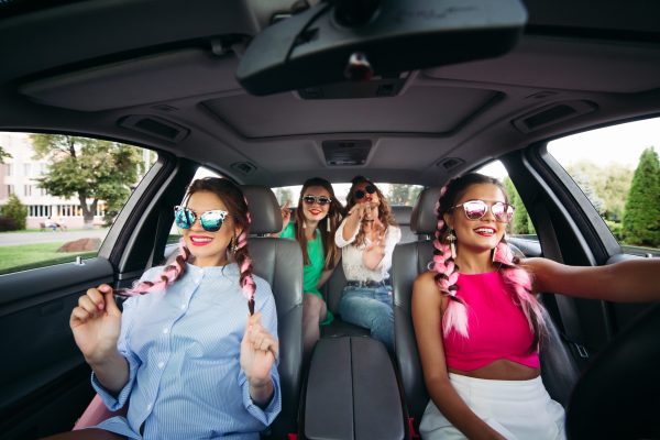 Trendy, stylish, trendy girlfriends go in the car listening to music and having fun together. They go shopping for their city. Friends rest together and shopping is always together.