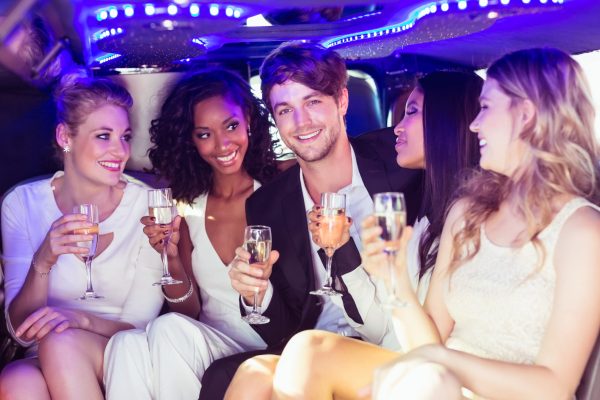 Happy friends drinking champagne in limousine